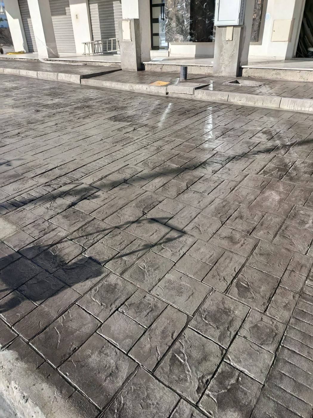 Béton estampé gris en dalles de pierre devant des commerces